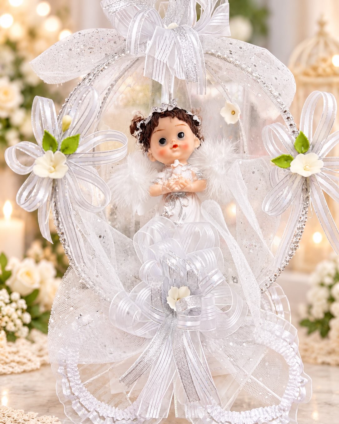Recuerdo de bautizo con muñequita vestida de blanco en un arreglo de tul y flores