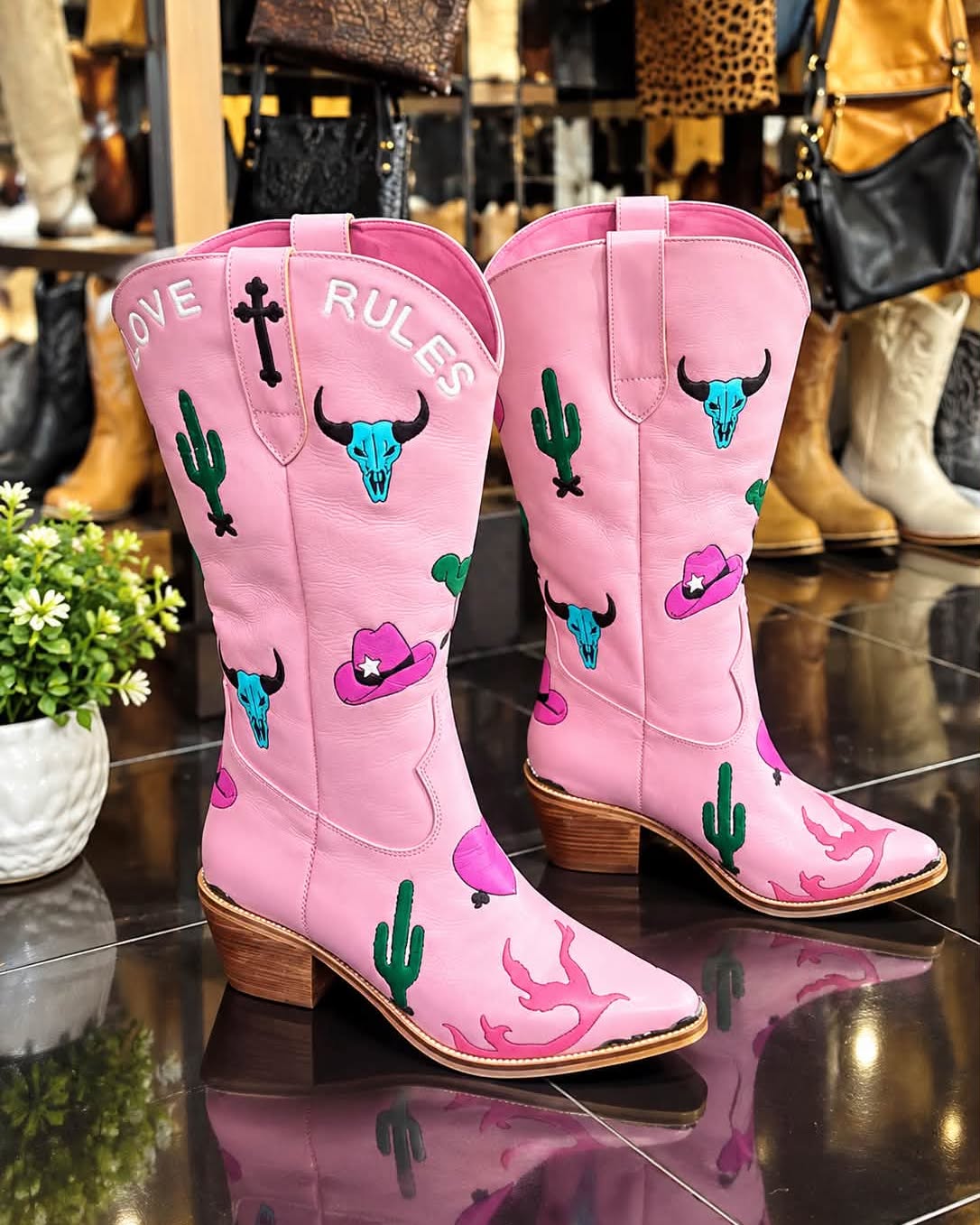 Pink leather boots with hand-carved Western motifs including cacti and cowboy hats in Legian boutique